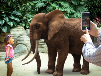 Kids standing next to virtual elephant with adult taking picture on phone