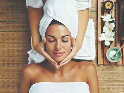 Woman at spa getting face massage with towel on head