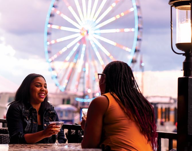 Young women having cocktails by Capital Wheel in National Harbor