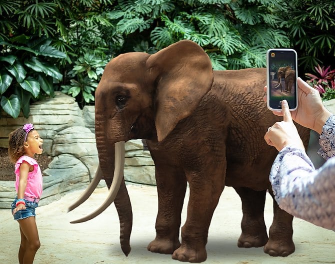 Two kids in front of virtual elephant while adult take picture on a phone