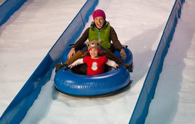 Female Adult and child on snow tubes on snow tubing lane