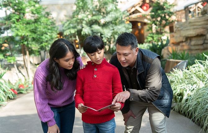 Two adults and child looking at scavenger hunt clues in Gaylord Palms Atrium