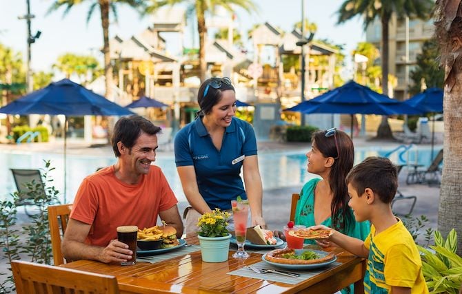 Family at dining table at SandBar next to resort pool at Gaylord Palms