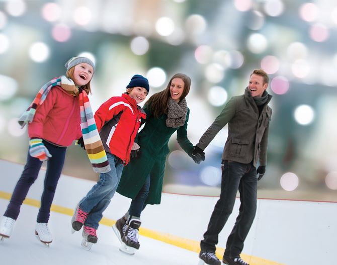 Family holiday hands in ice skates on ice skating rink
