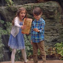 Two kids holding scavenger hunt instructions next to waterfall