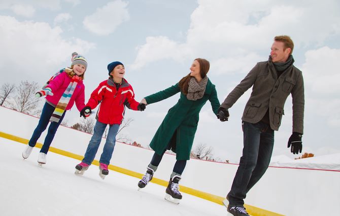 Family on ice skating rink holding hands