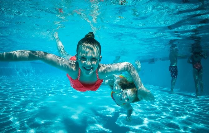 Kids swimming underwater in resort pool