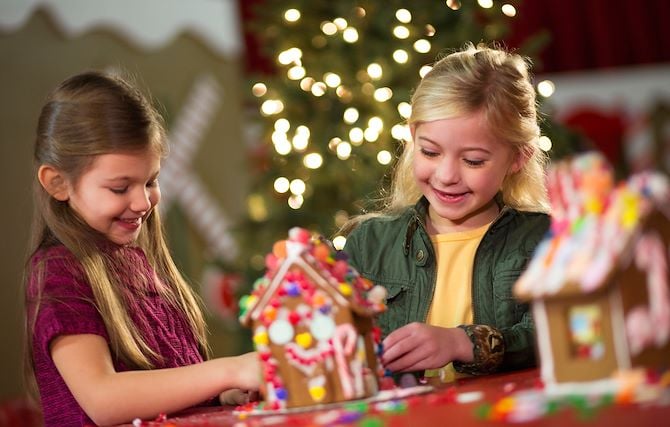 Two young girls decorating a Gingerbread house