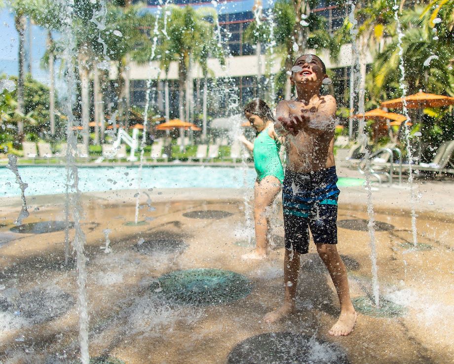 Children playing in an outdoor, sunny splash pad.