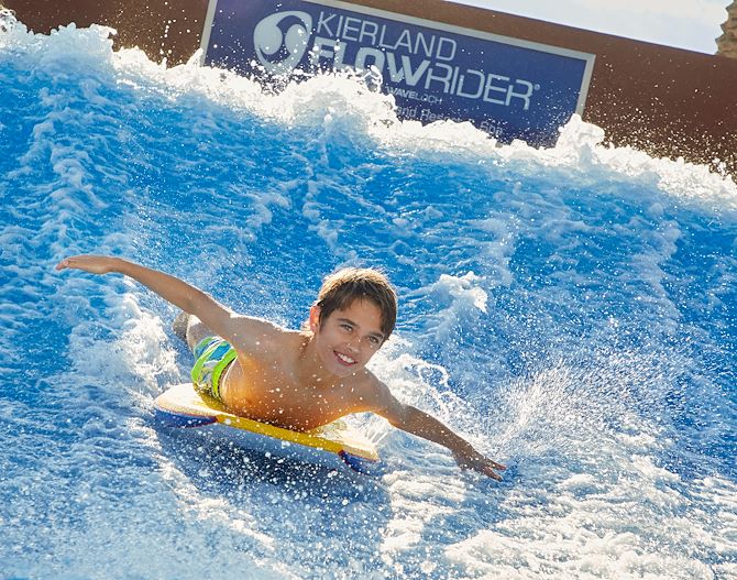 Boy riding on a board on the FlowRider wave machine.